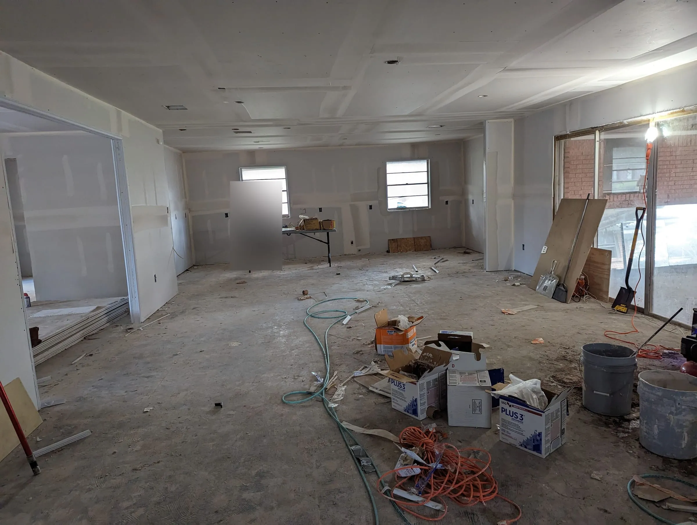 Open interior with new drywall hung and materials on the slab