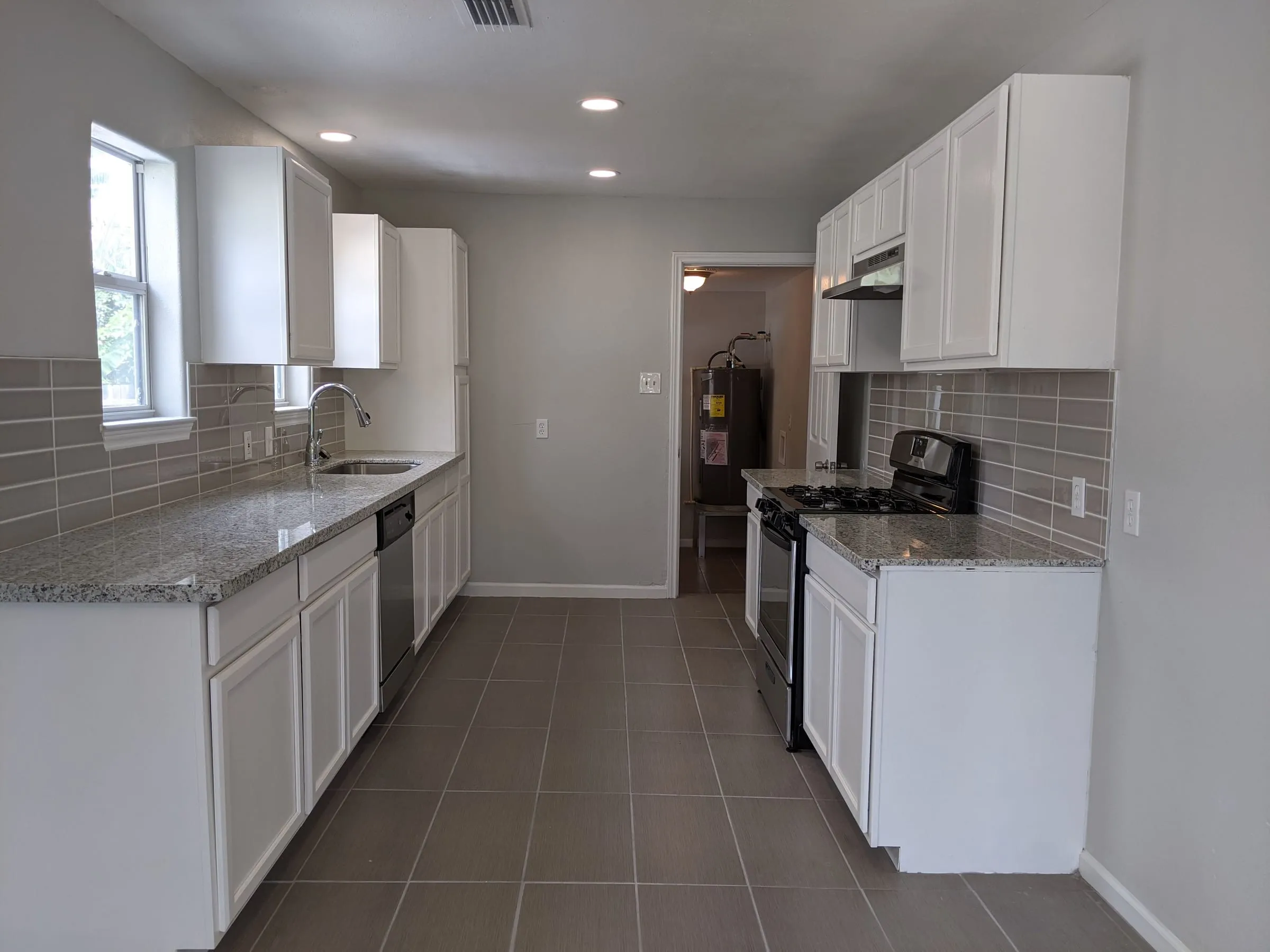 Renovated galley kitchen with white shaker cabinets and granite counters