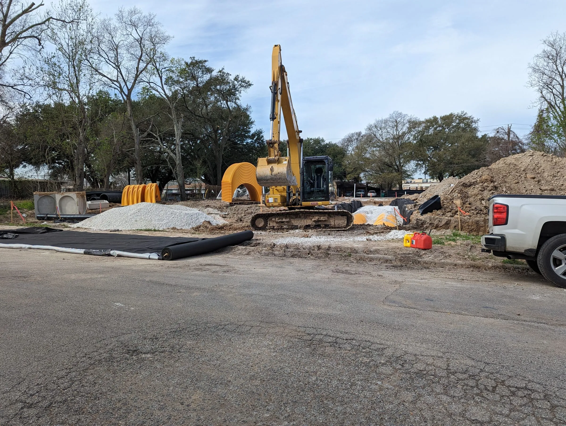 Excavator on a cleared site beside stormwater detention chambers
