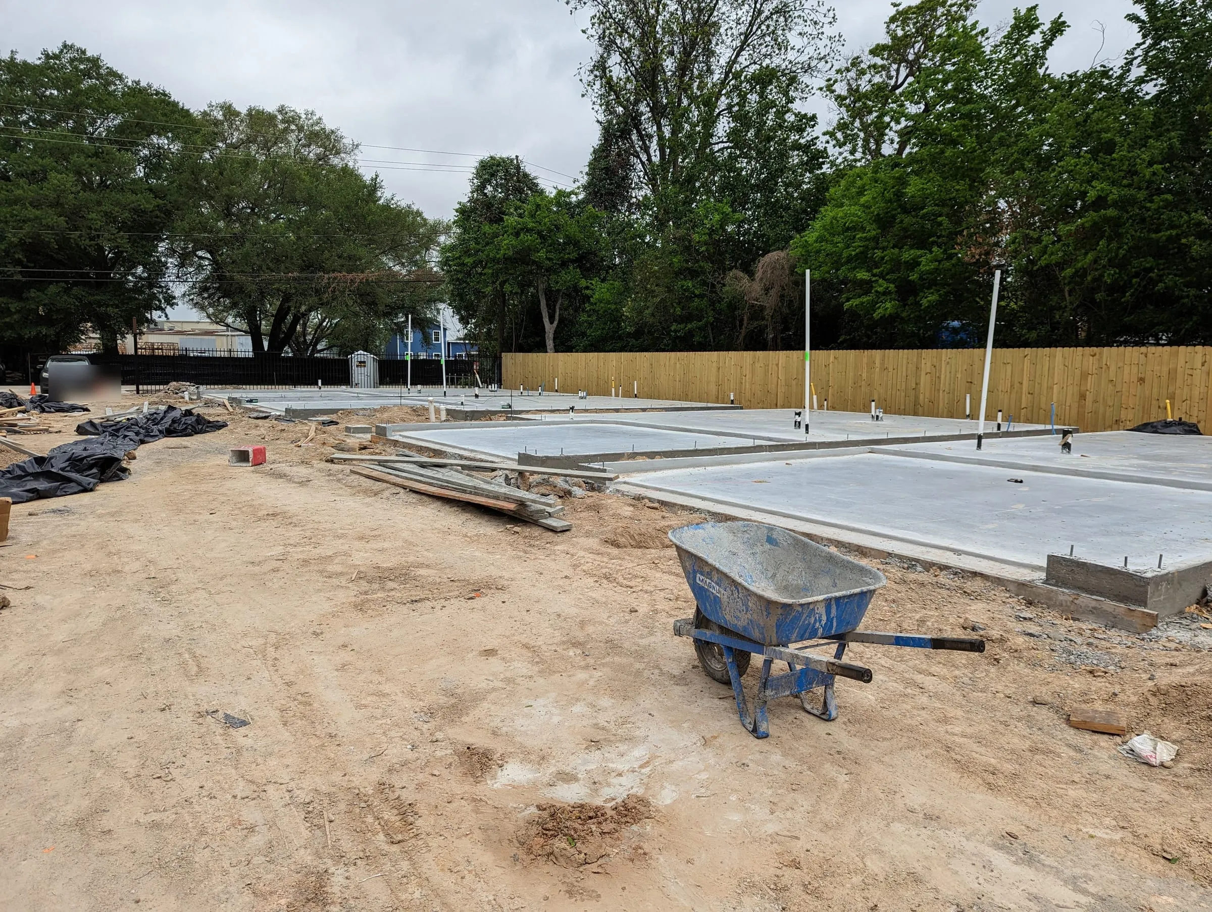 Freshly poured concrete slabs beside a new wood fence