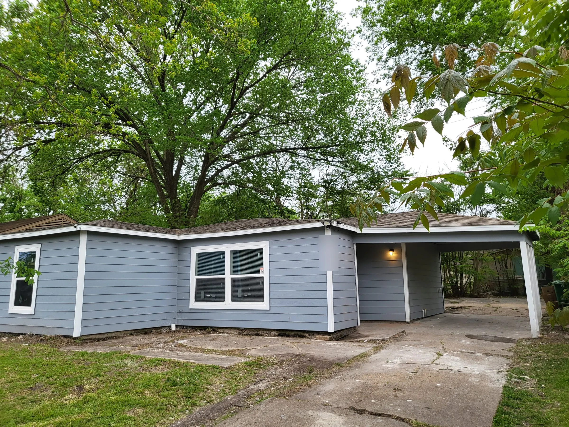 Renovated blue-gray house with a carport under mature trees
